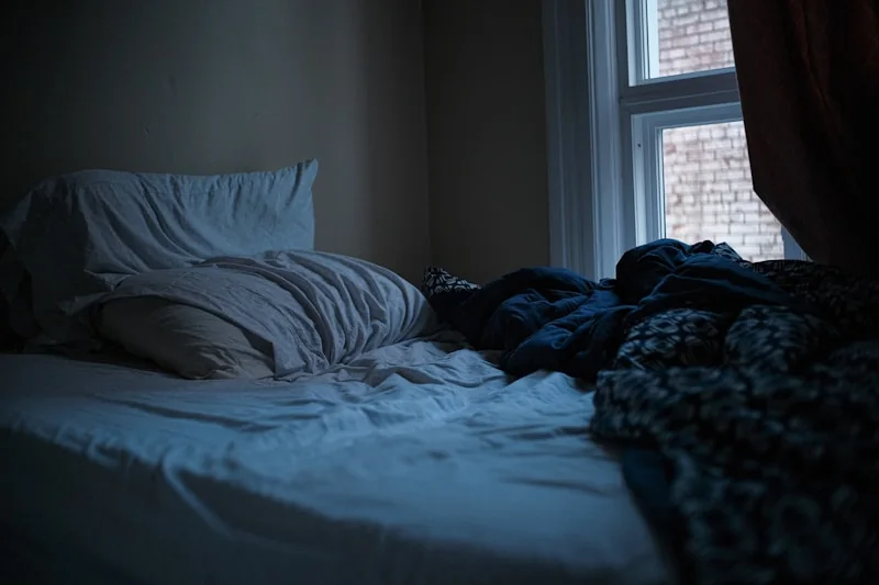 A bedside table at night with a phone and a glass of water.